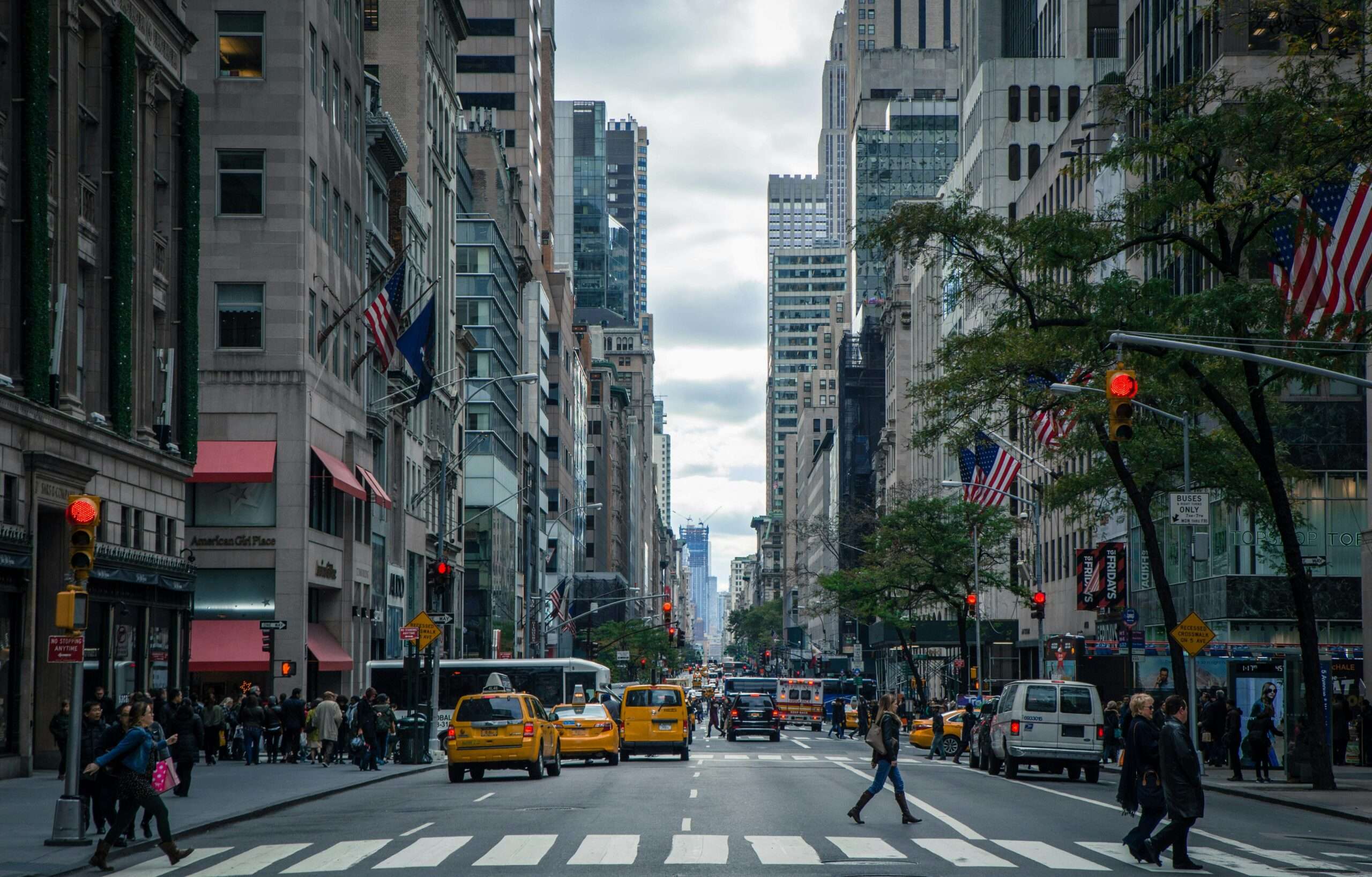 A New York City street with people, cars and buildings.