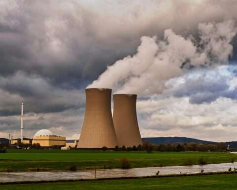 Two nuclear silos pouring gas into the air before large clouds.