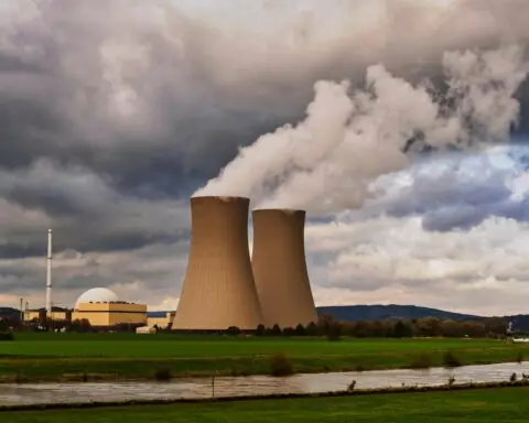 Two nuclear silos pouring gas into the air before large clouds.