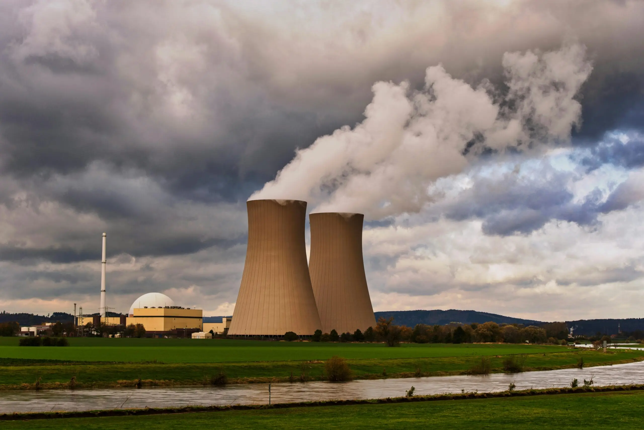 Two nuclear silos pouring gas into the air before large clouds.