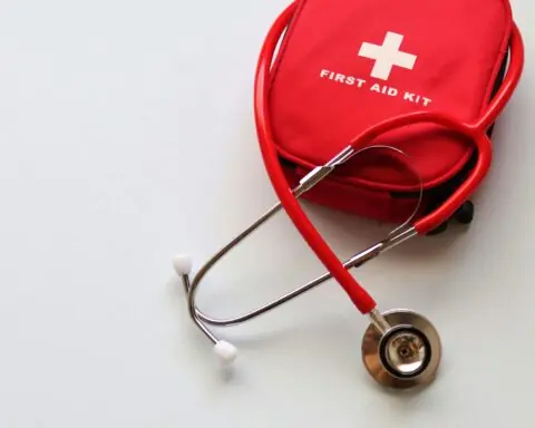 A red first aid kit and a stethoscope against a white table.