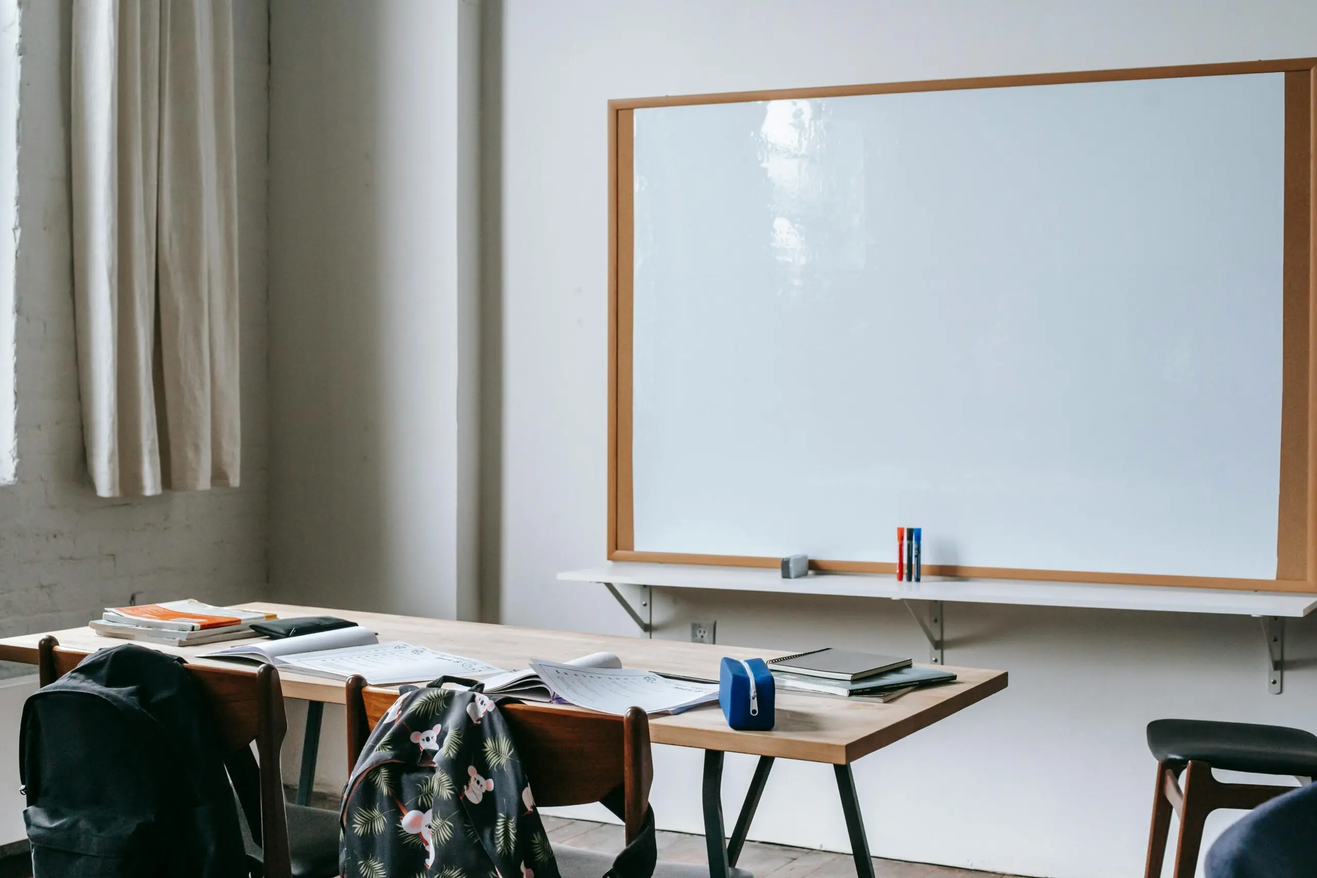 A whiteboard behind a desk in a classroom.