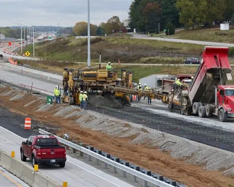 Workers construction highway improvements on a stretch of roadway.