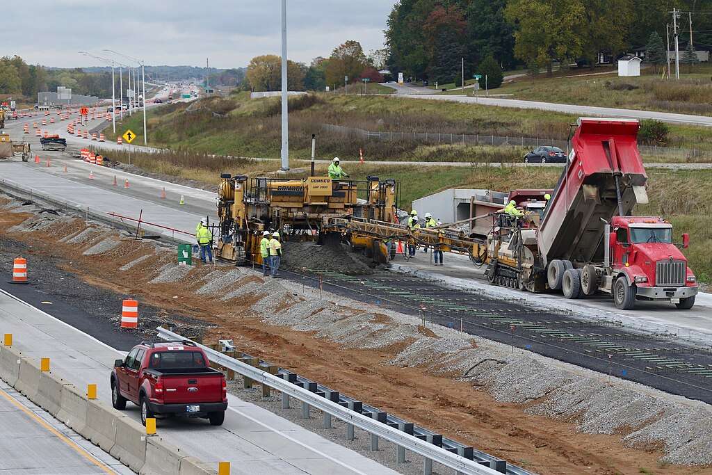 Workers construction highway improvements on a stretch of roadway.