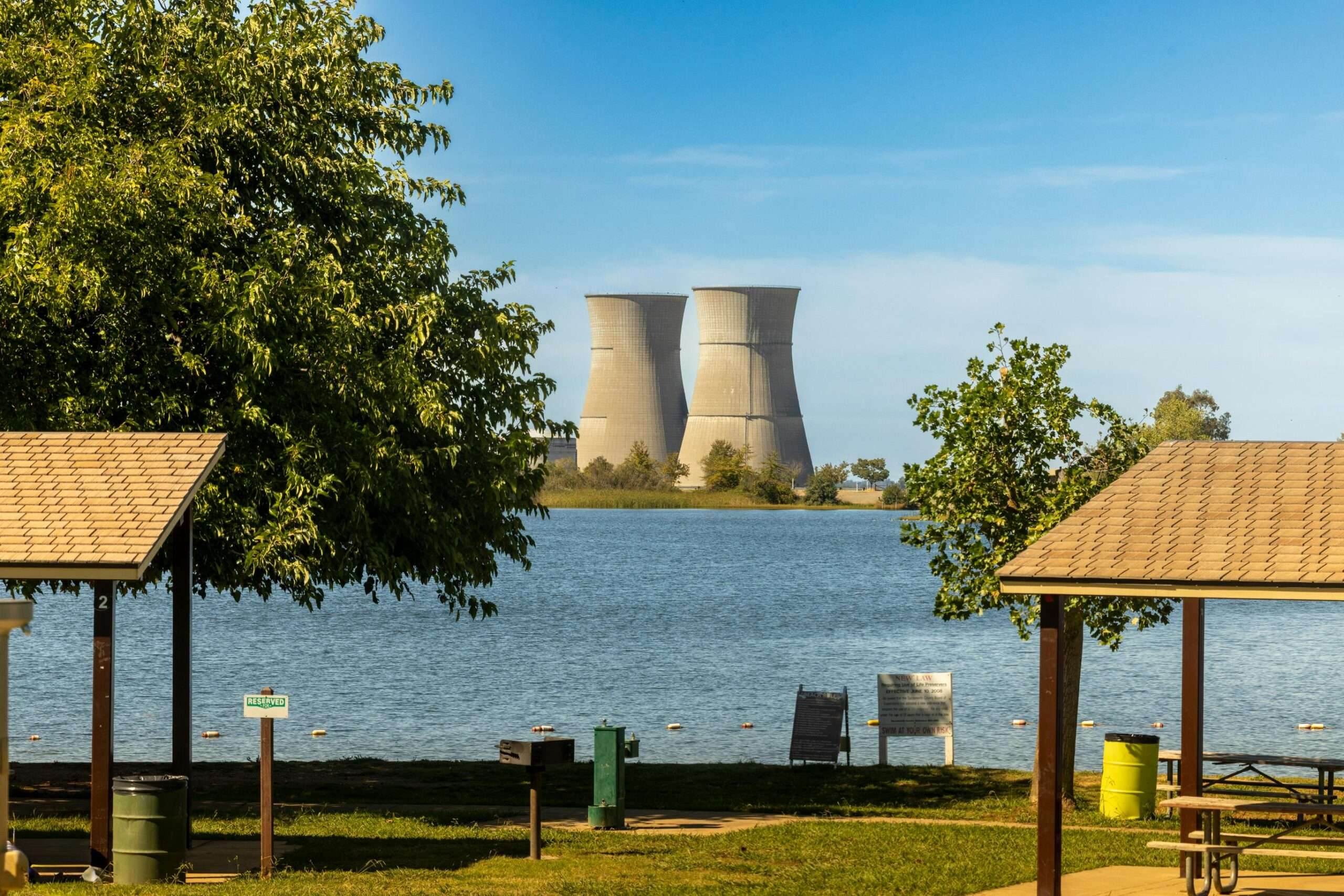 Nuclear cooling towers through trees and canopies at a park.