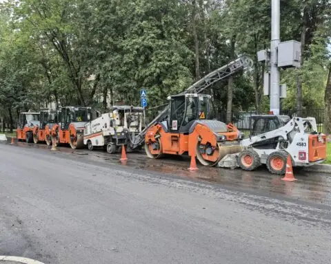 Work vehicles sit alongside a boulevard to prepare for construction.