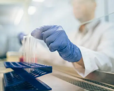 A medical researcher places a small beaker into a tray.
