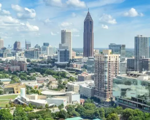 A distant shot of the Atlanta skyline with greenery and office buildings on a sunny day.