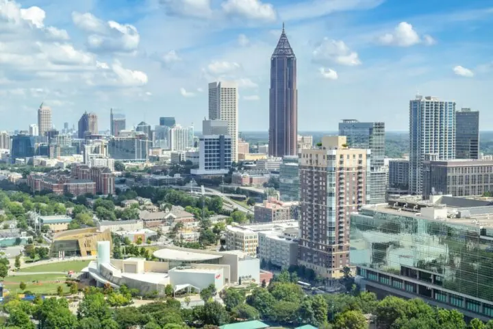 A distant shot of the Atlanta skyline with greenery and office buildings on a sunny day.