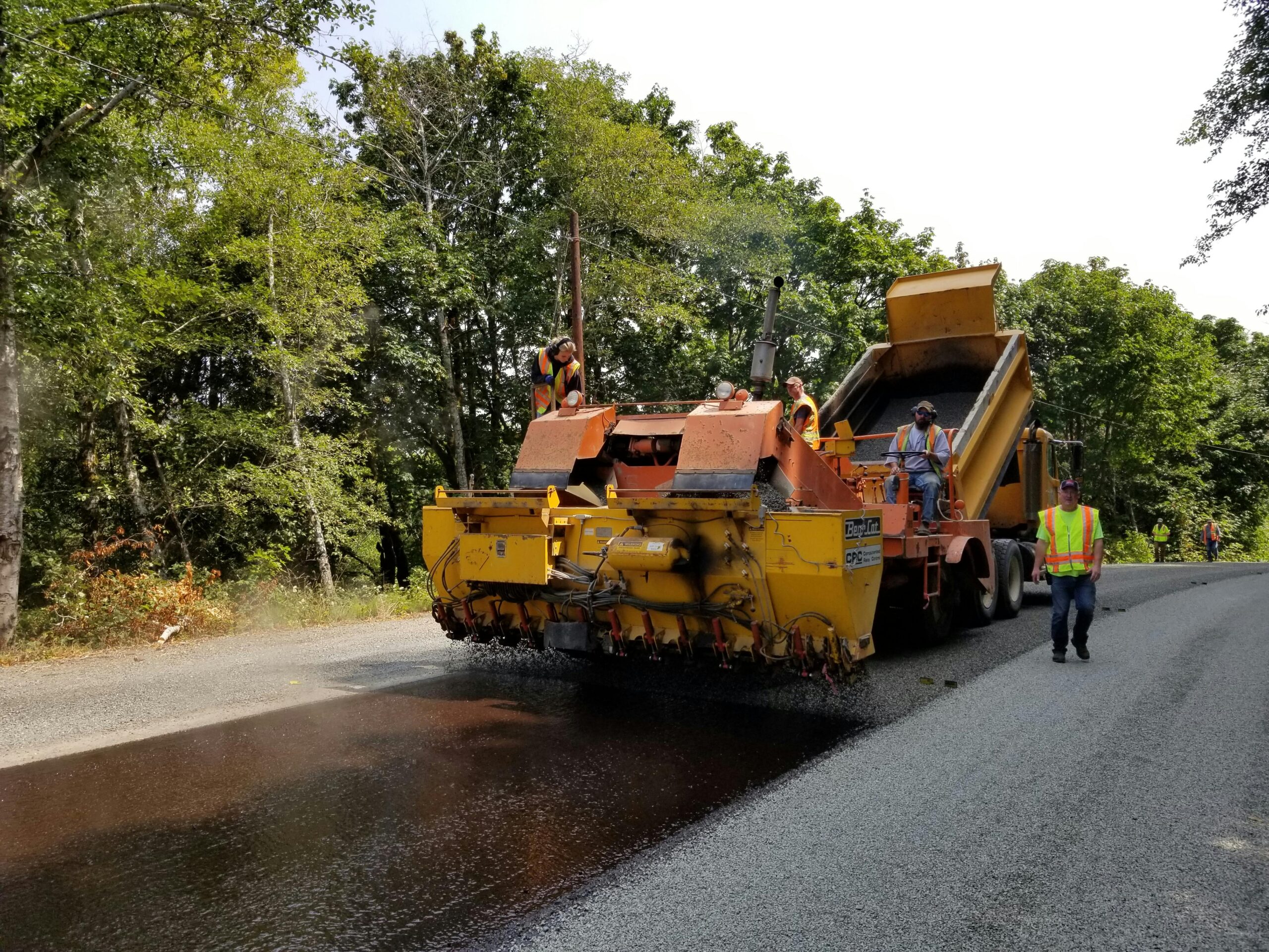 A roller machine rolls over freshly laid asphalt.