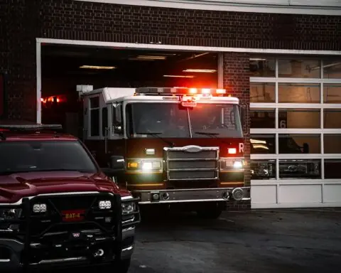 A fire truck with light on leaving a fire station.