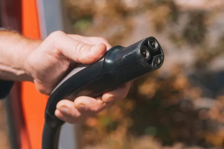 A hand holding a electric vehicle charging cable.