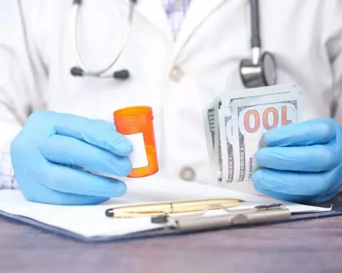 A doctor holds an empty pill bottle and cash.