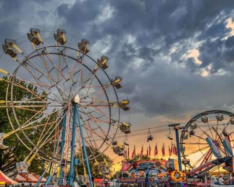 Ferris wheels before a setting sun at a fairground.