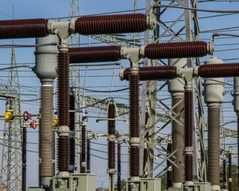 Several power transformers before a blue sky.