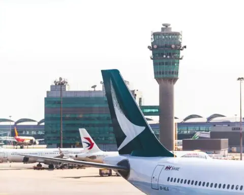 The tail of an airplane before an air traffic control tower at an airport.