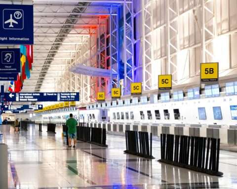 An airport terminal with a person and standing escalator.