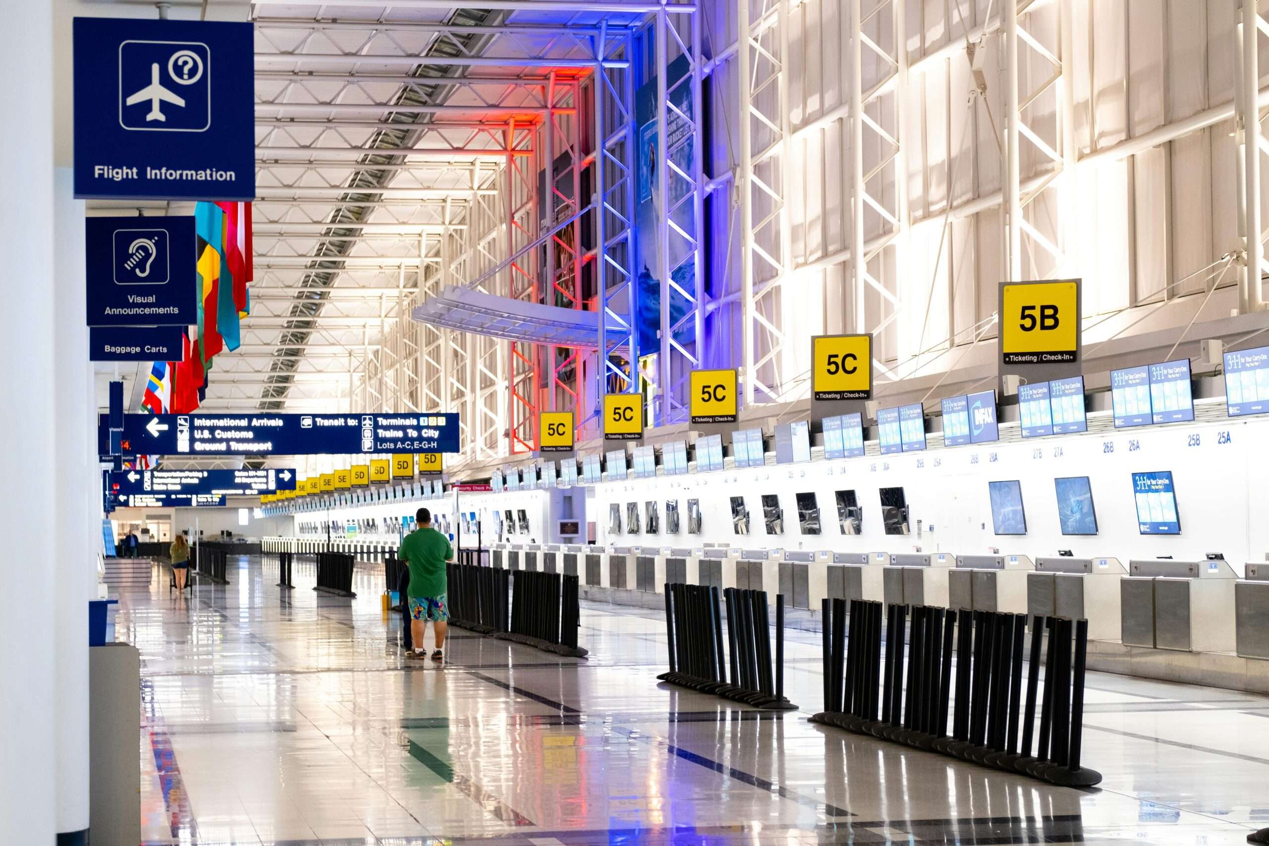 An airport terminal with a person and standing escalator.
