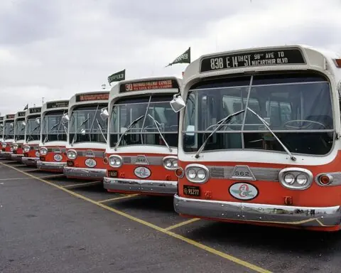 A row of red buses at a maintenance facility.