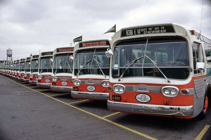 A row of red buses at a maintenance facility.