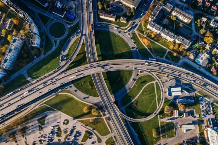 An aerial view of a highway intersection nearby houses, trees and infrastructure.