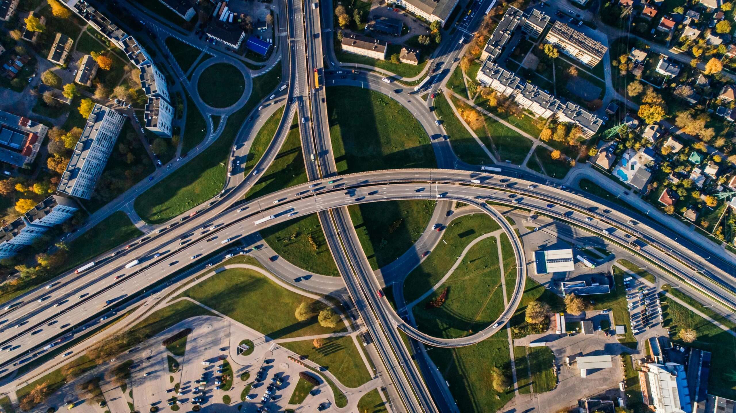 An aerial view of a highway intersection nearby houses, trees and infrastructure.