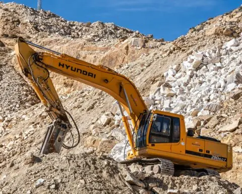 A yellow construction vehicle on a rock pile in a construction site.