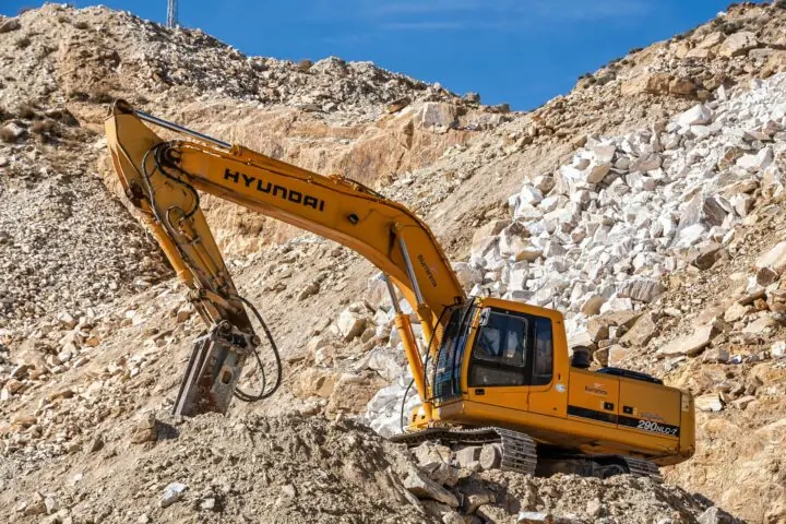A yellow construction vehicle on a rock pile in a construction site.