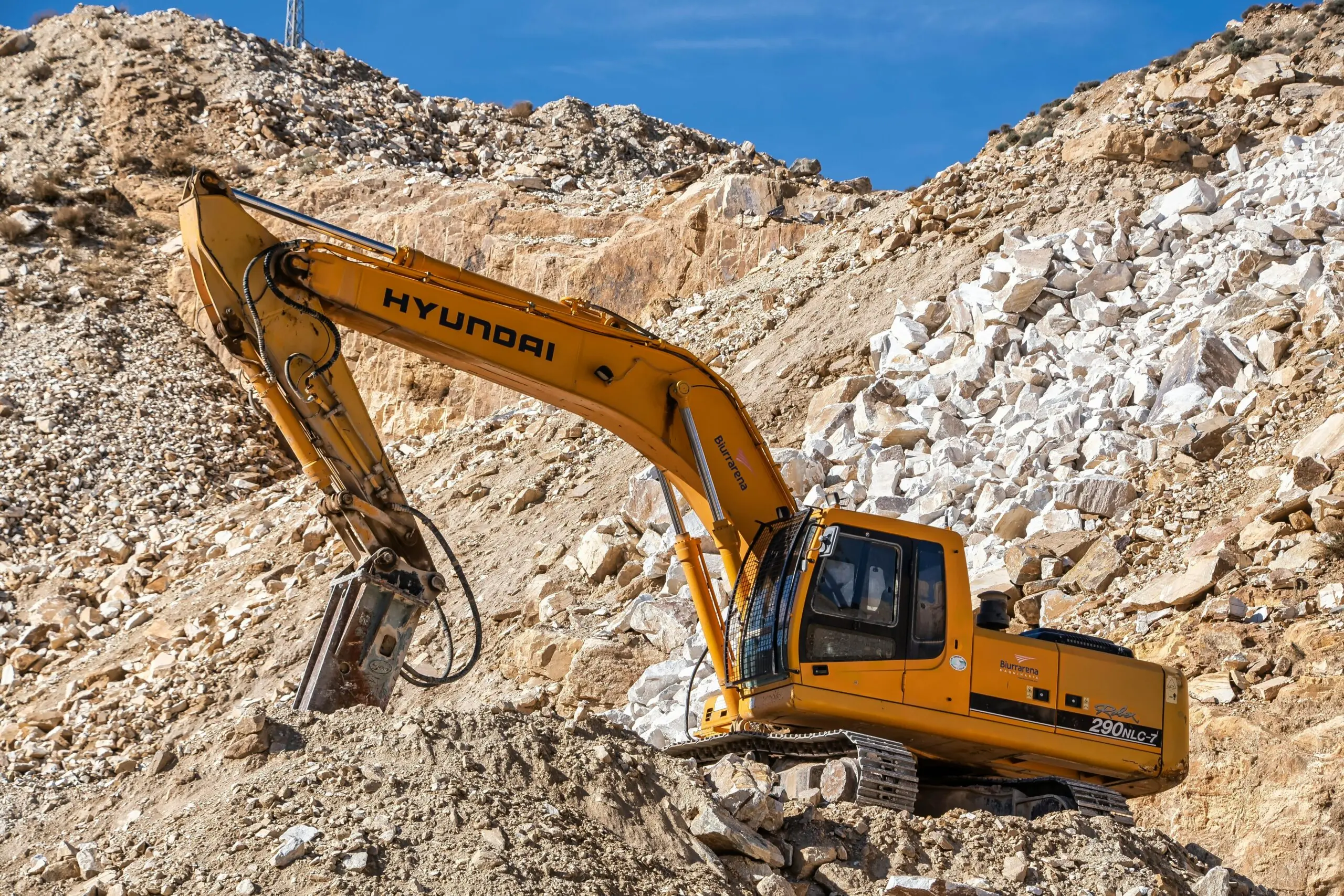 A yellow construction vehicle on a rock pile in a construction site.