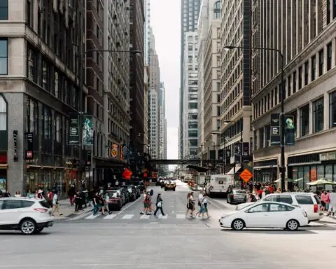 A city street in Chicago funded partially by state funding with people and cars.