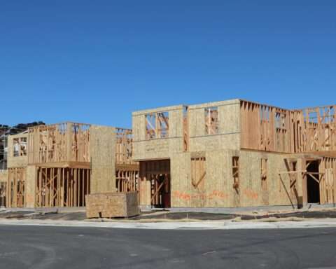 A partially constructed housing development before a blue sky.