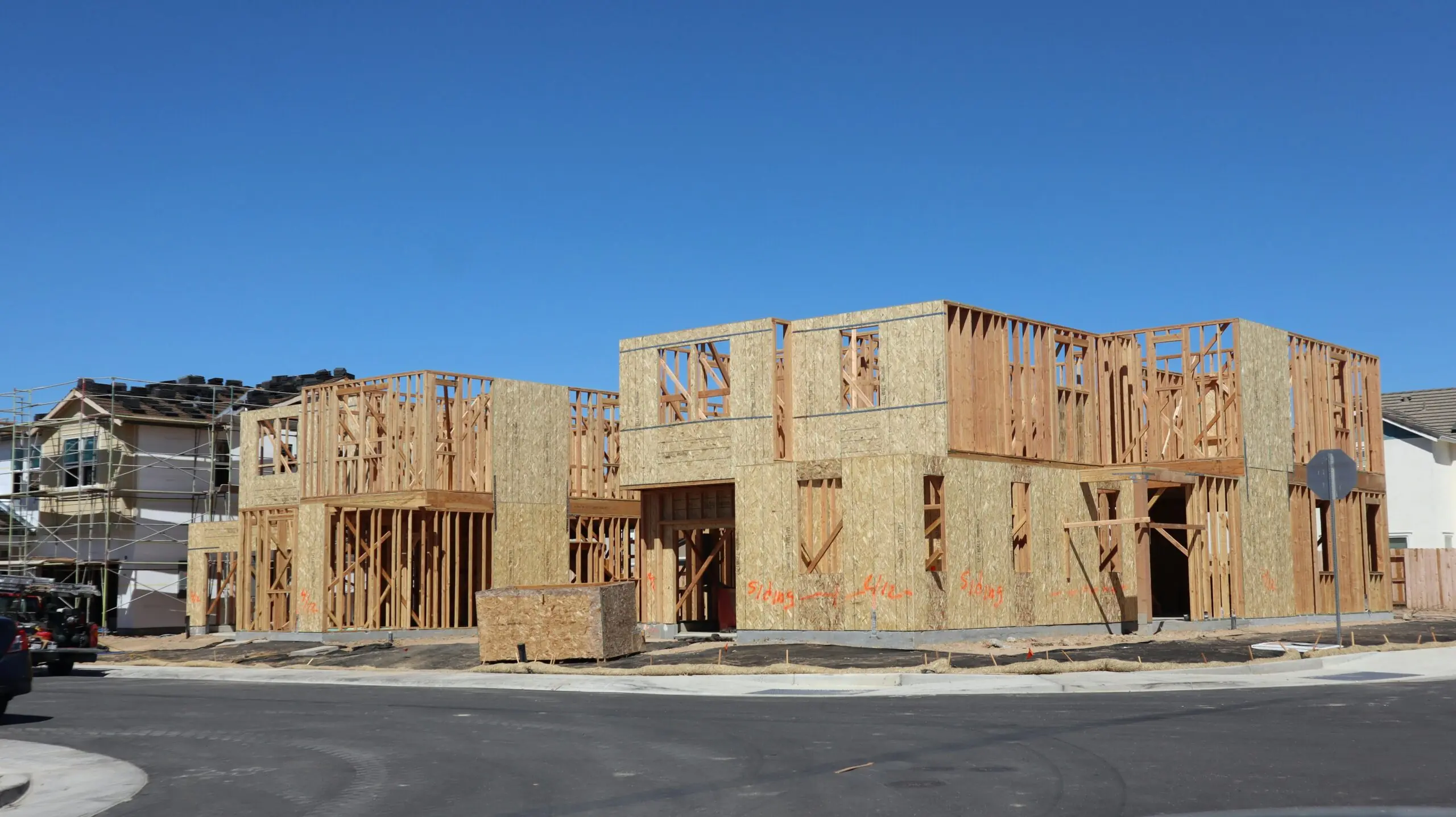 A partially constructed housing development before a blue sky.