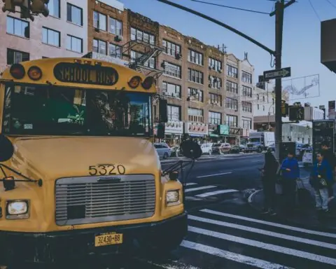 A yellow school bus along a busy street in New York City.