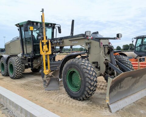 A construction vehicle on dirt before a blue sky.
