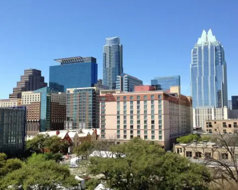The Austin city skyline before a blue sky.