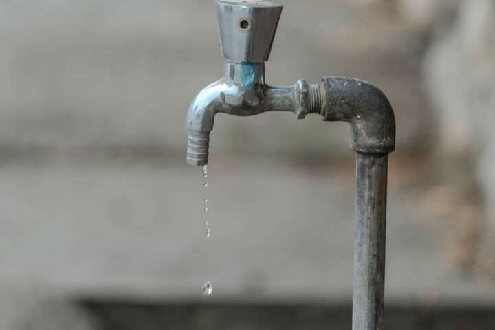 A water pipe dripping water onto a sidewalk.