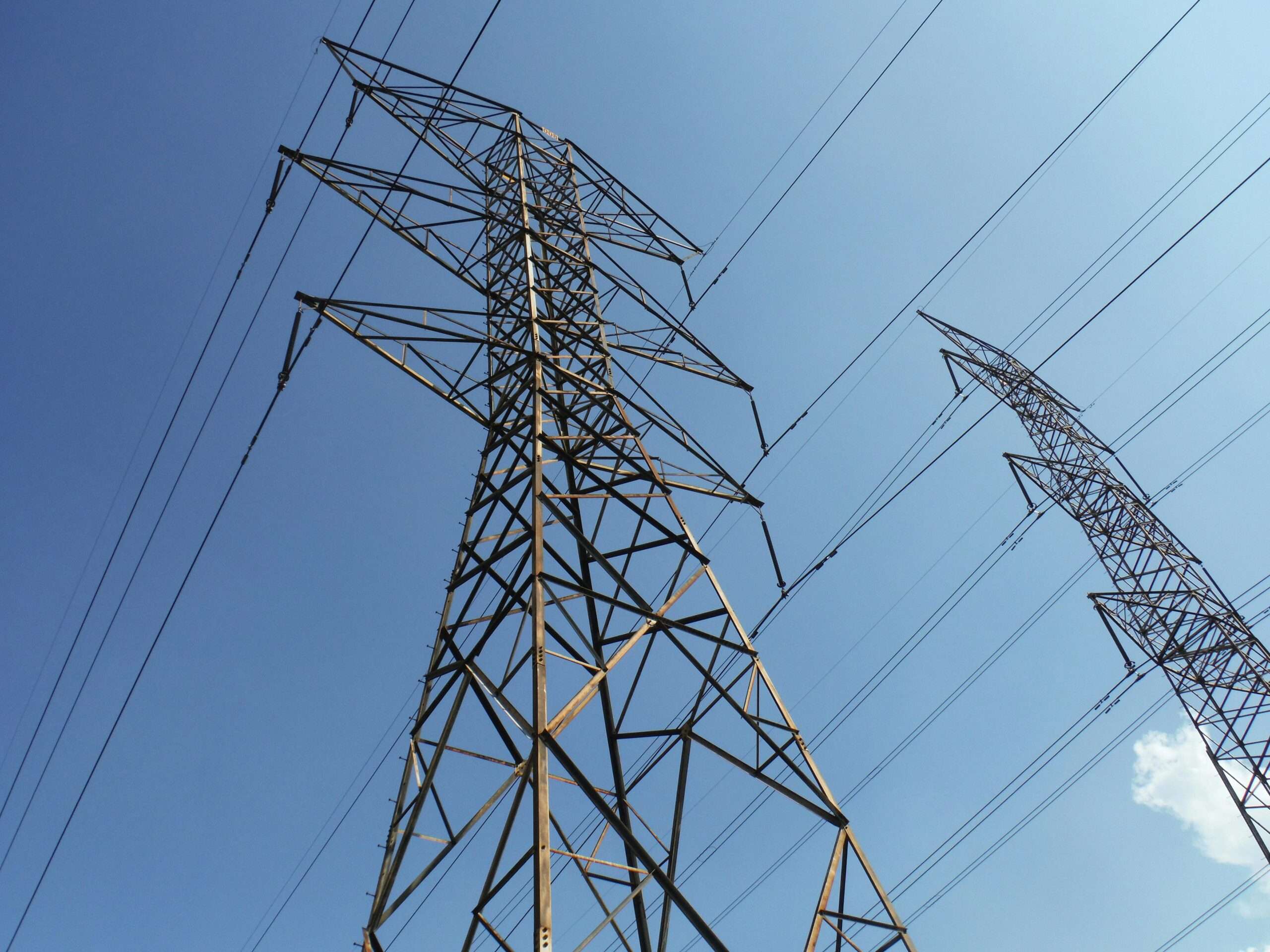 Two energy transmission towers before a blue sky.