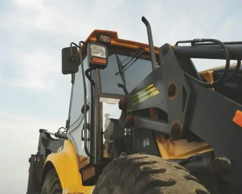 A yellow construction vehicle before a cloudy sky.