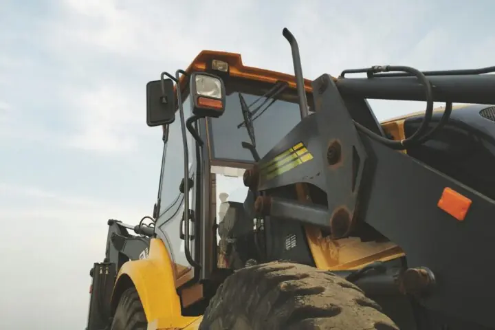 A yellow construction vehicle before a cloudy sky.