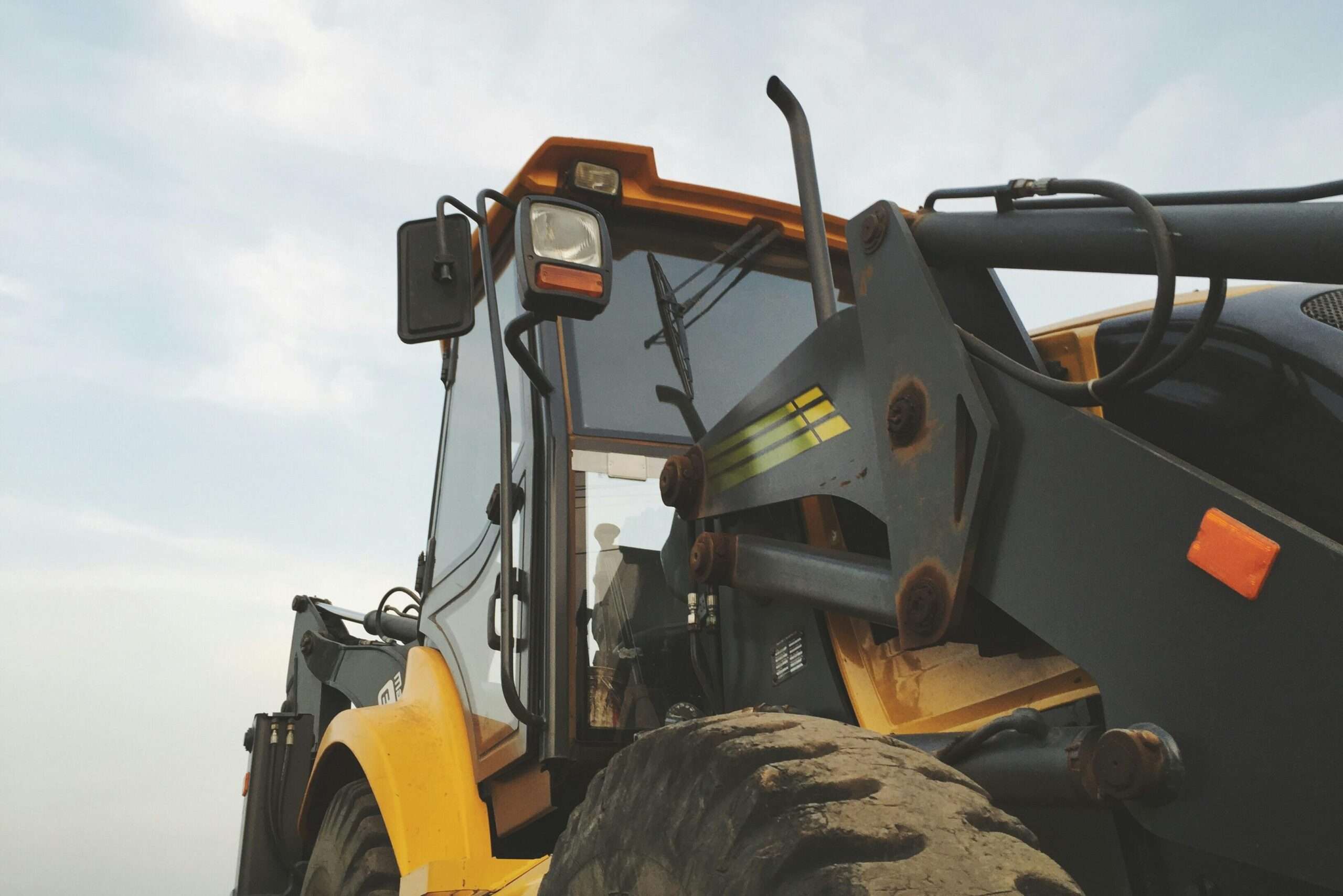 A yellow construction vehicle before a cloudy sky.