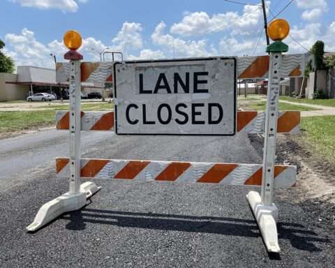 A Construction sign in the middle of an empty road.