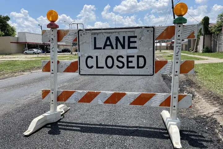 A Construction sign in the middle of an empty road.