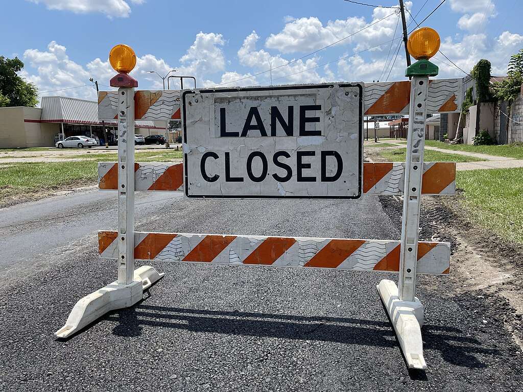 A Construction sign in the middle of an empty road.