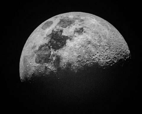 A partially illuminated Moon before a dark, black universe.