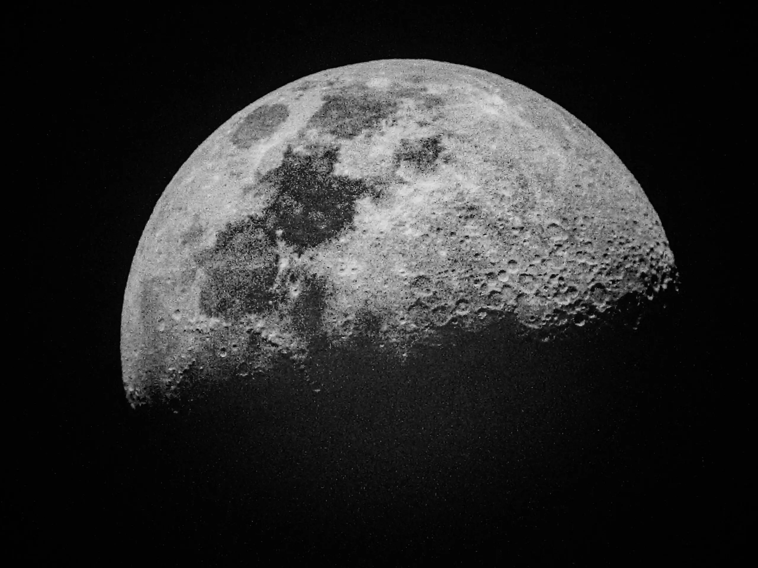 A partially illuminated Moon before a dark, black universe.
