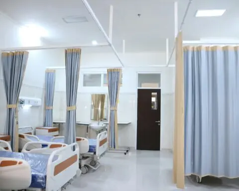 A room in a hospital with beds and a curtain.