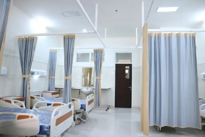 A room in a hospital with beds and a curtain.