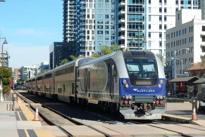 A Pacific Surfliner train in California nearby homes and roads.