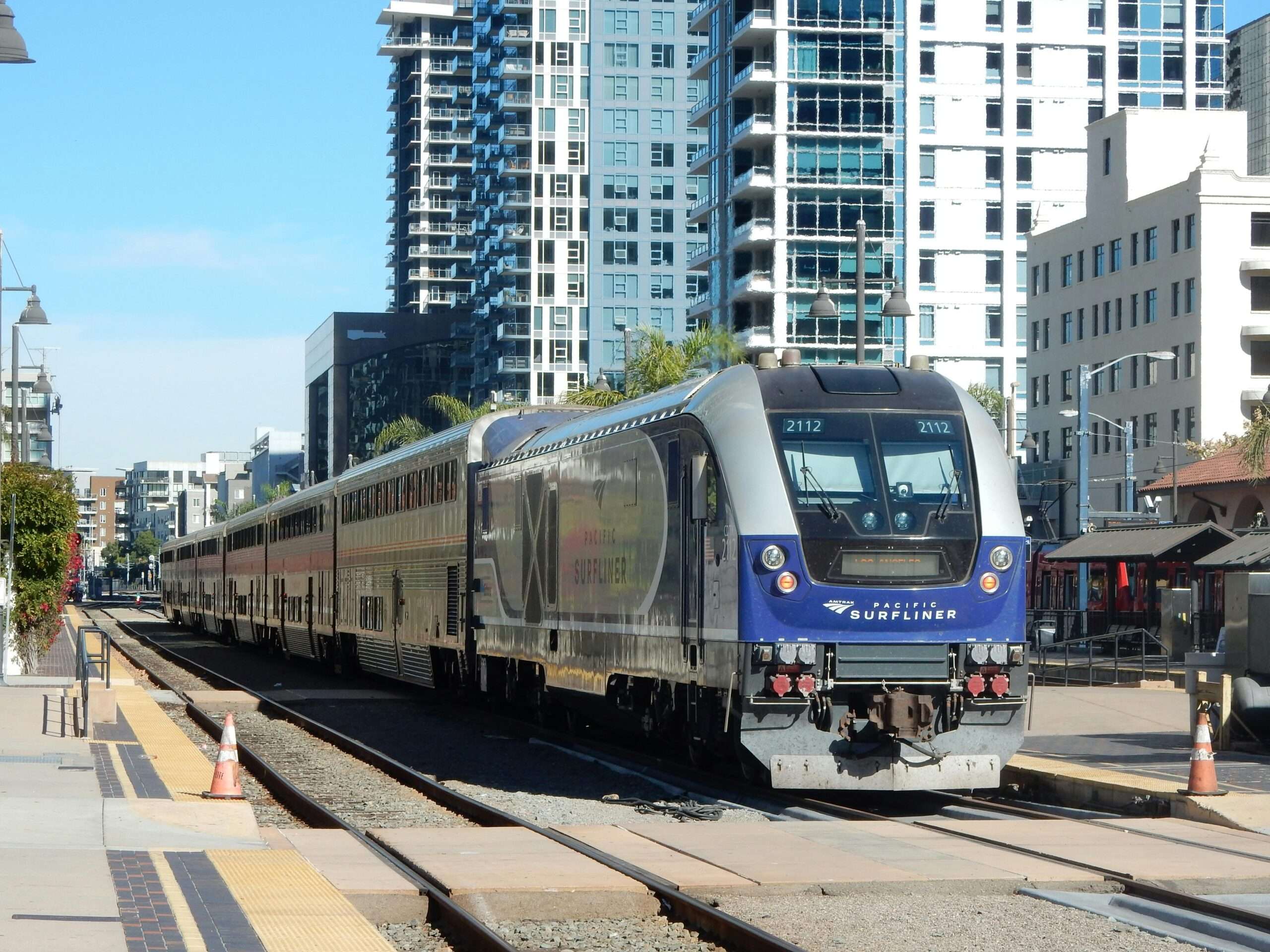 A Pacific Surfliner train in California nearby homes and roads.