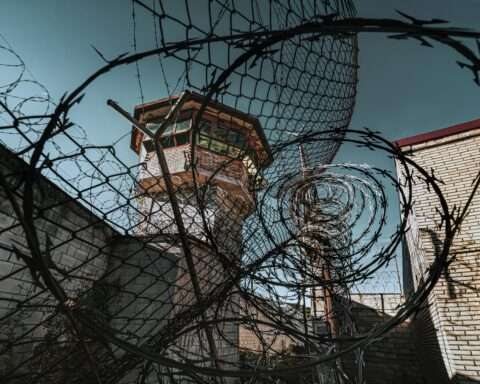 A jail watch tower through barbed wire at a jail.